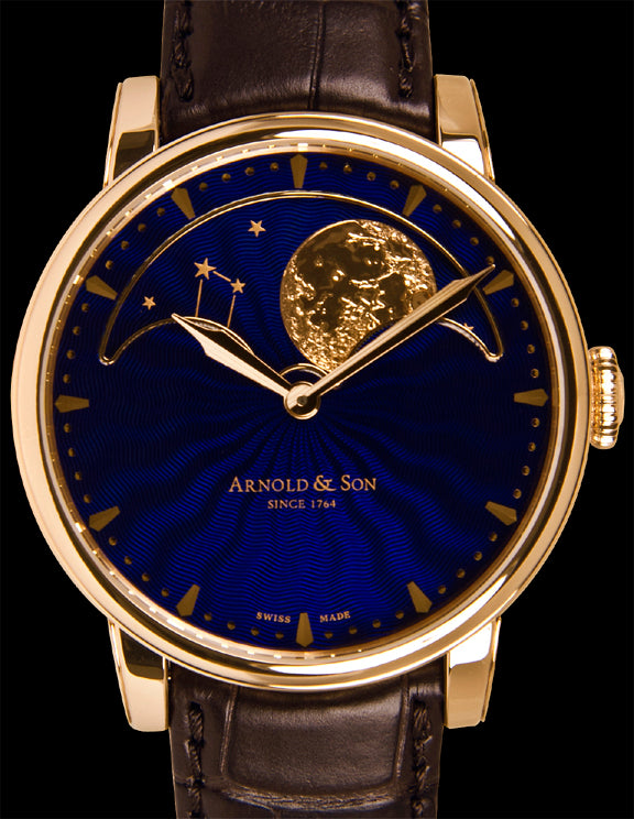 With an 18k red gold case this watch has a sapphire crystal over the dial.  The crystal is coated with an anti-reflective treatment on both sides. The lacquered guilloché dial is blue and displays a golden moon and stars on the top half of the dial.  This watch is powered by the manual wind A&S1512 in-house caliber movement. This is one of the most precise moon phase calendars on the market with only a one day deviation every 122 years.  The functions include hours, minutes, and moon phases.